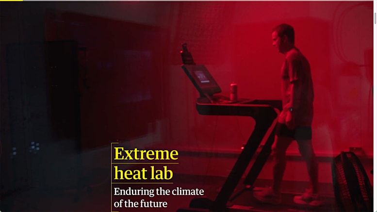 A man is walking on a treadmill in a room that is shaded deep red from the glow of heat lamps.