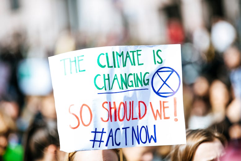 Photo of a sign carried at a protest: The climate is changing, so should we! #ActNow.